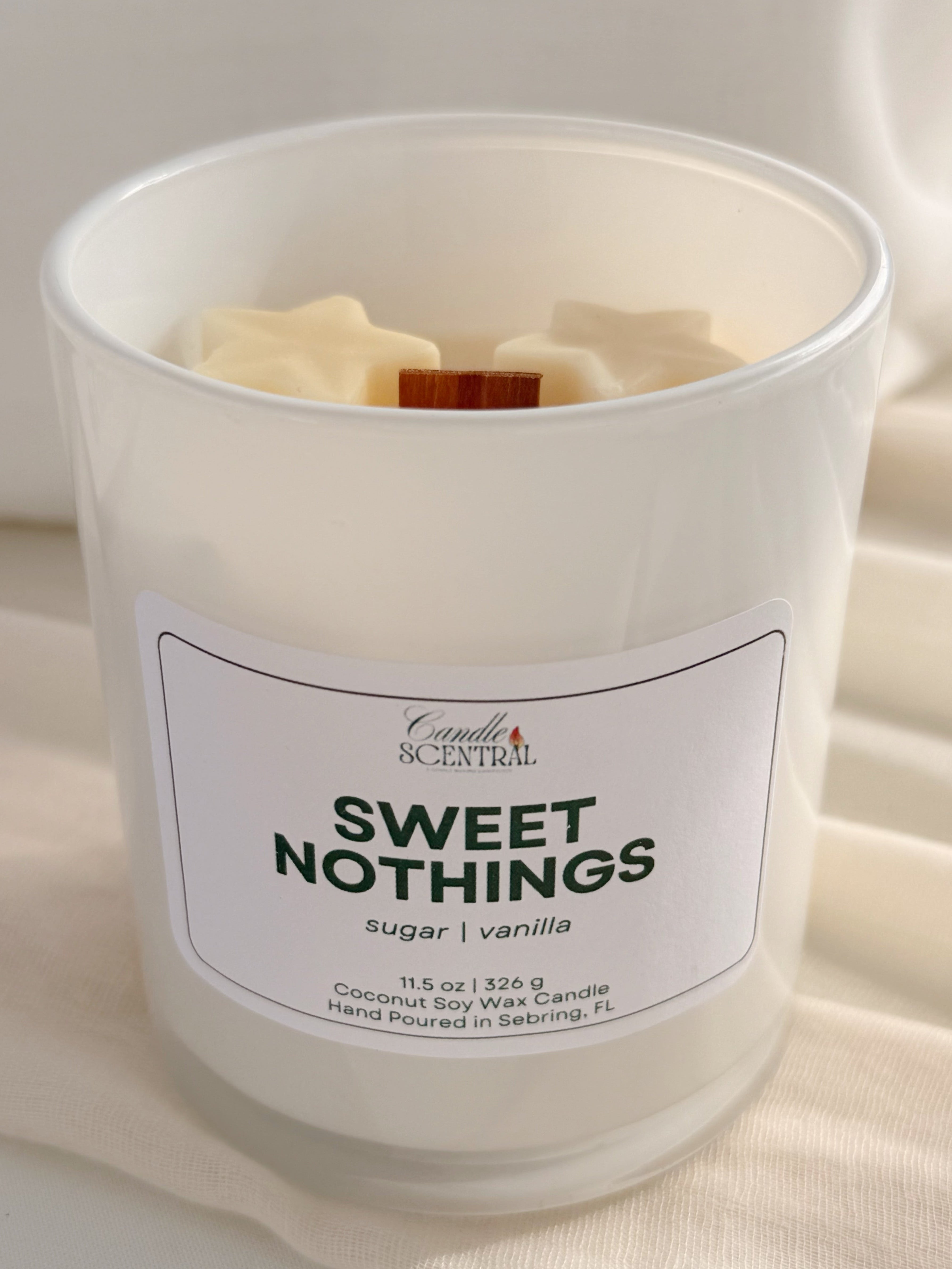 A white glass candle with a label that says "Sweet Nothings" along with the scent notes of sugar and vanilla.