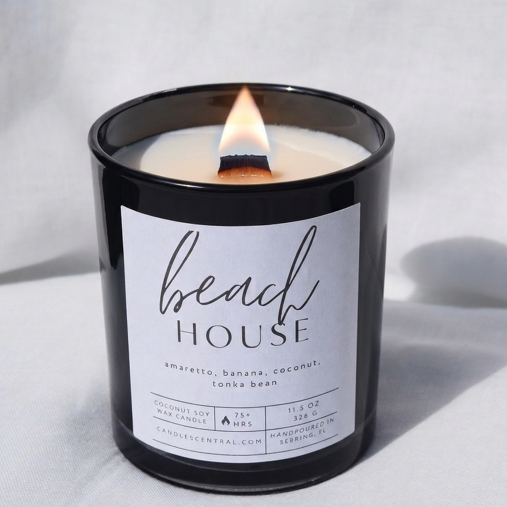 Picture of a candle burning with a label that says "Beach House" along with the fragrance notes of amaretto, banana, coconut, and tonka bean