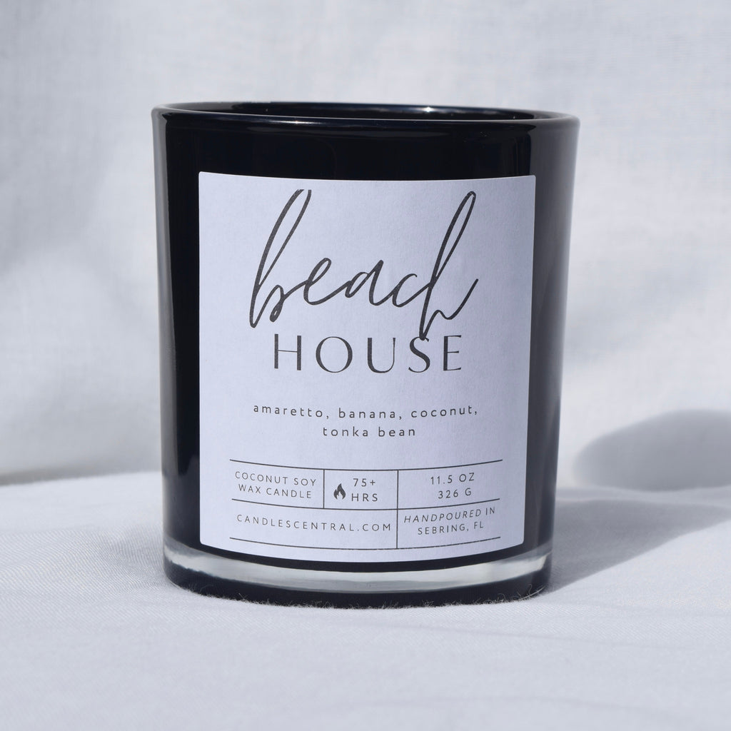 Picture of a candle with a label that says "Beach House" along with the fragrance notes of amaretto, banana, coconut, and tonka bean