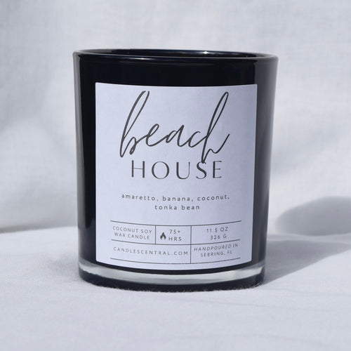 Picture of a candle with a label that says "Beach House" along with the fragrance notes of amaretto, banana, coconut, and tonka bean