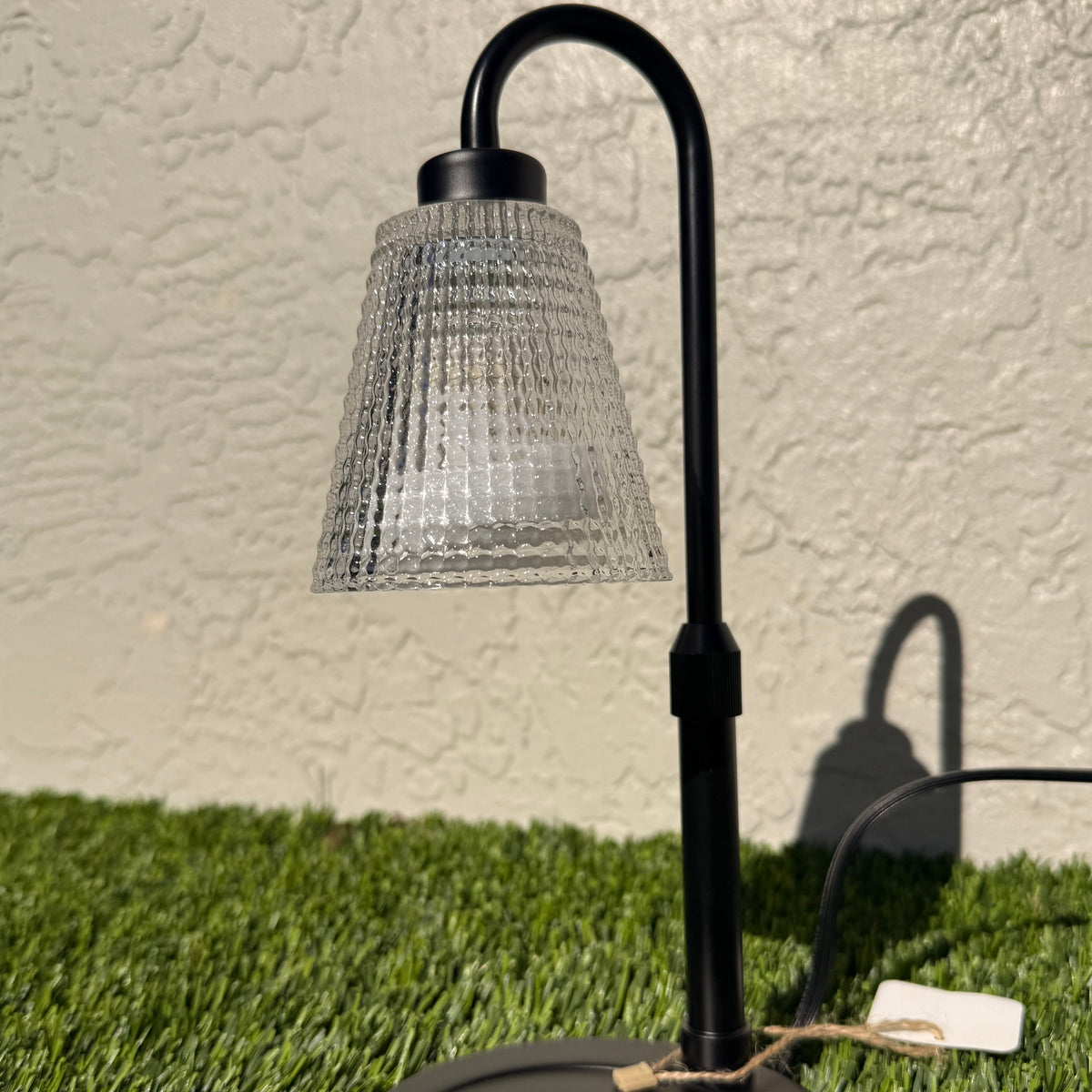 A picture of a candle warming lamp sitting on grass.