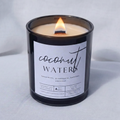 Picture of a candle burning with a label that says "Coconut Waters" along with the fragrance notes of spearmint, pineapple, bamboo, and coconut