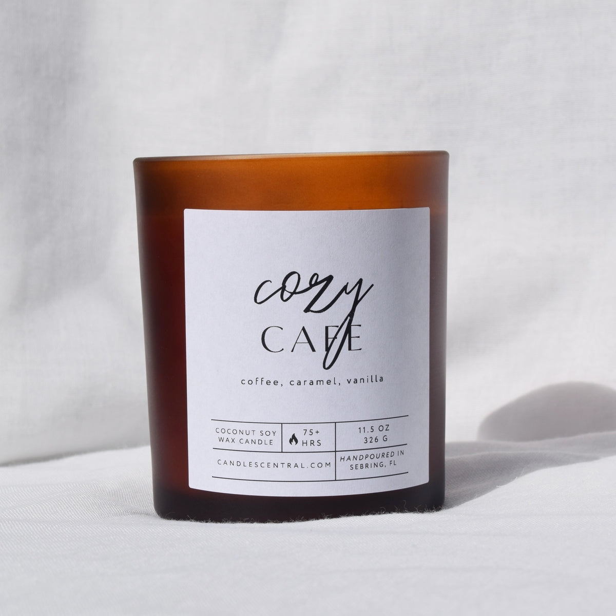 Picture of a candle with a label that says "Cozy Cafe" along with the fragrance notes of coffee, caramel, and vanilla