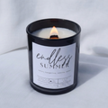 Picture of a candle burning with a label that says "Endless Summer" along with the fragrance notes of neroli, tangerine, vanilla, and cedar 