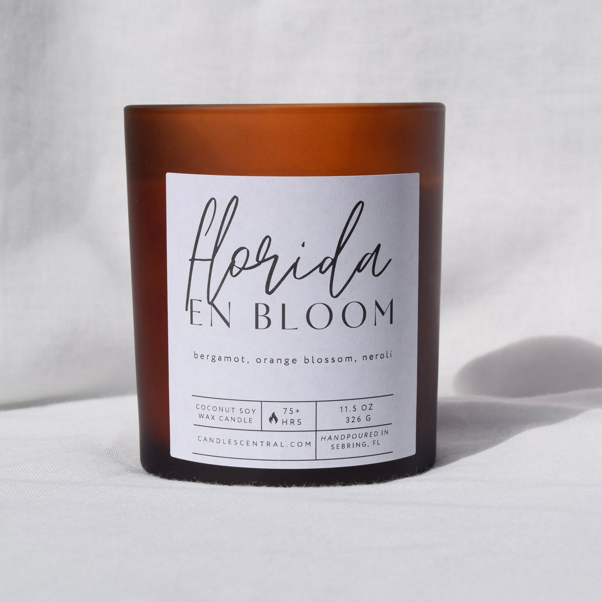 Picture of a candle with a label that says "Florida en Bloom" along with the fragrance notes of bergamot, orange blossom, and neroli