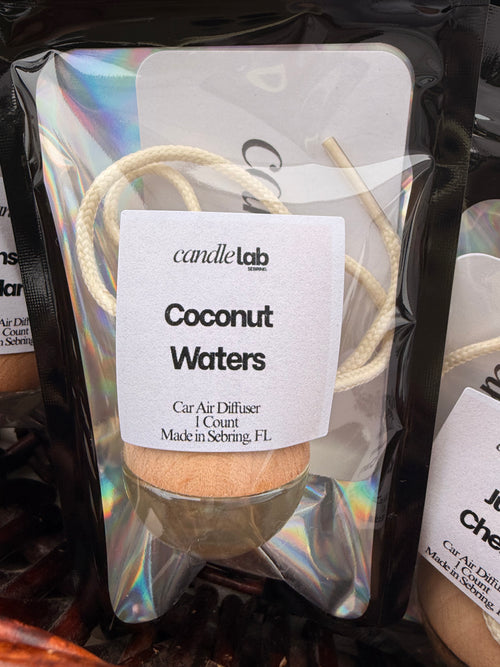 Picture of a small bag with a car diffuser inside and a label on the front reading "Coconut Waters. Car Air Diffuser. 1 Count. Made in Sebring, FL"