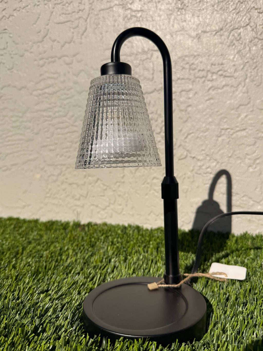 A picture of a candle warming lamp sitting on grass.