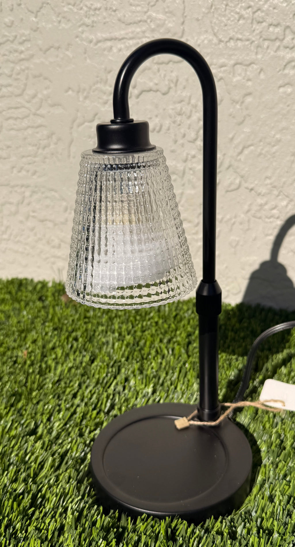 A picture of a candle warming lamp sitting on grass.