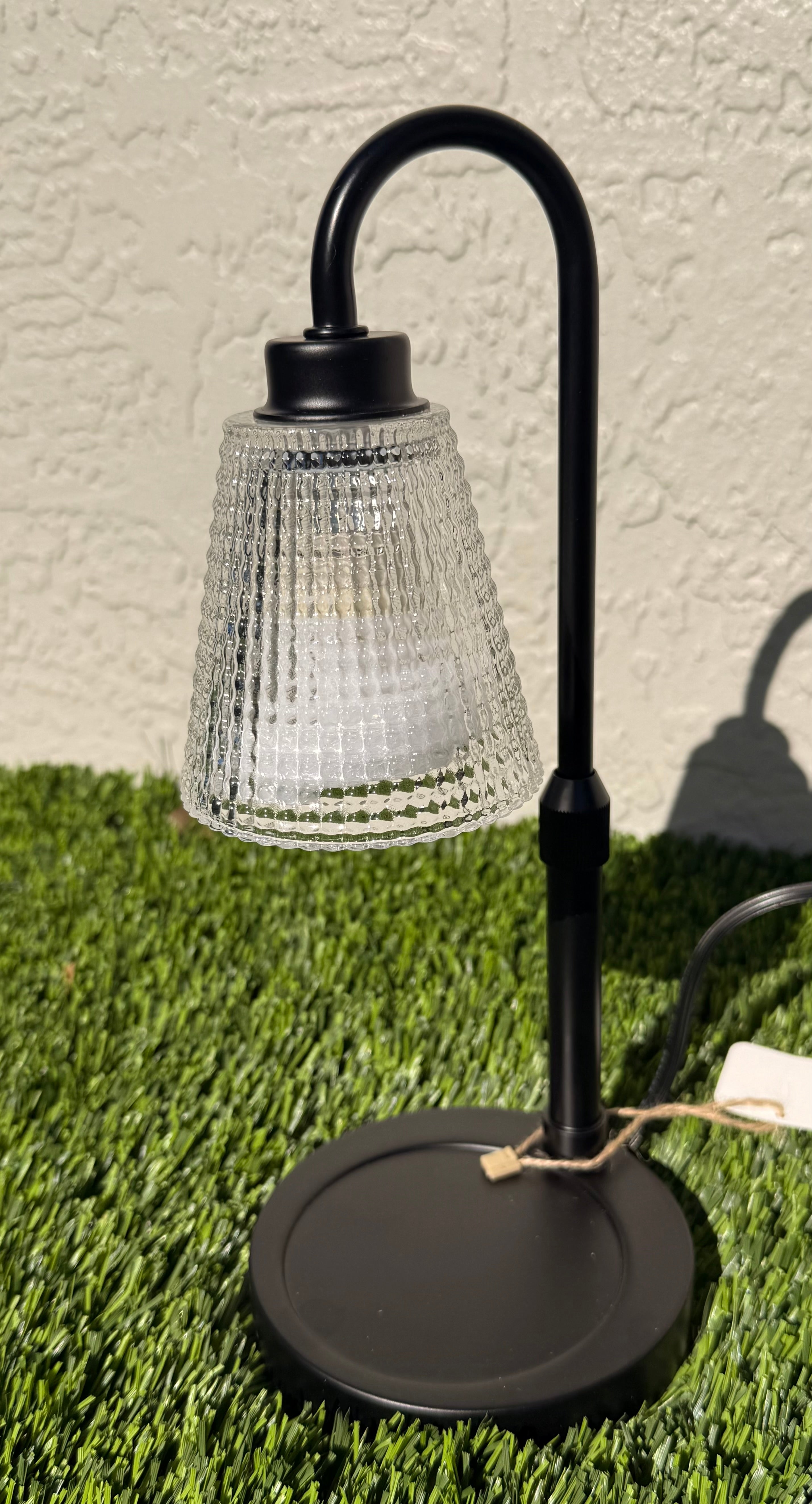 A picture of a candle warming lamp sitting on grass.