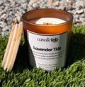 An amber glass candle with a label that says "Lavender Tide" along with a short blurb that reads "The scent of lavender floats through the breeze as the tide rolls in and crashes on sun-bleached driftwood, leaving a trail of calm and serenity in its wake."