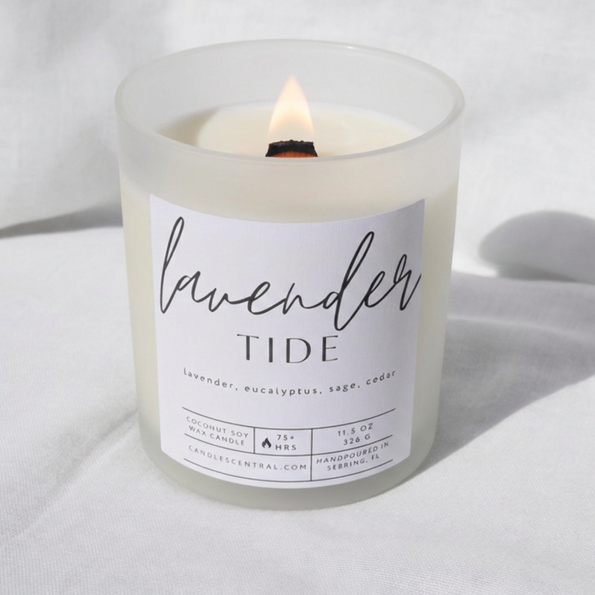 Picture of a candle burning with a label that says "Lavender Tide" along with the fragrance notes of lavender, eucalyptus, sage, and cedar