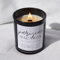 Picture of a candle burning with a label that says "Parisian Macaron" along with the fragrance notes of almond, cinnamon, vanilla, and sugar