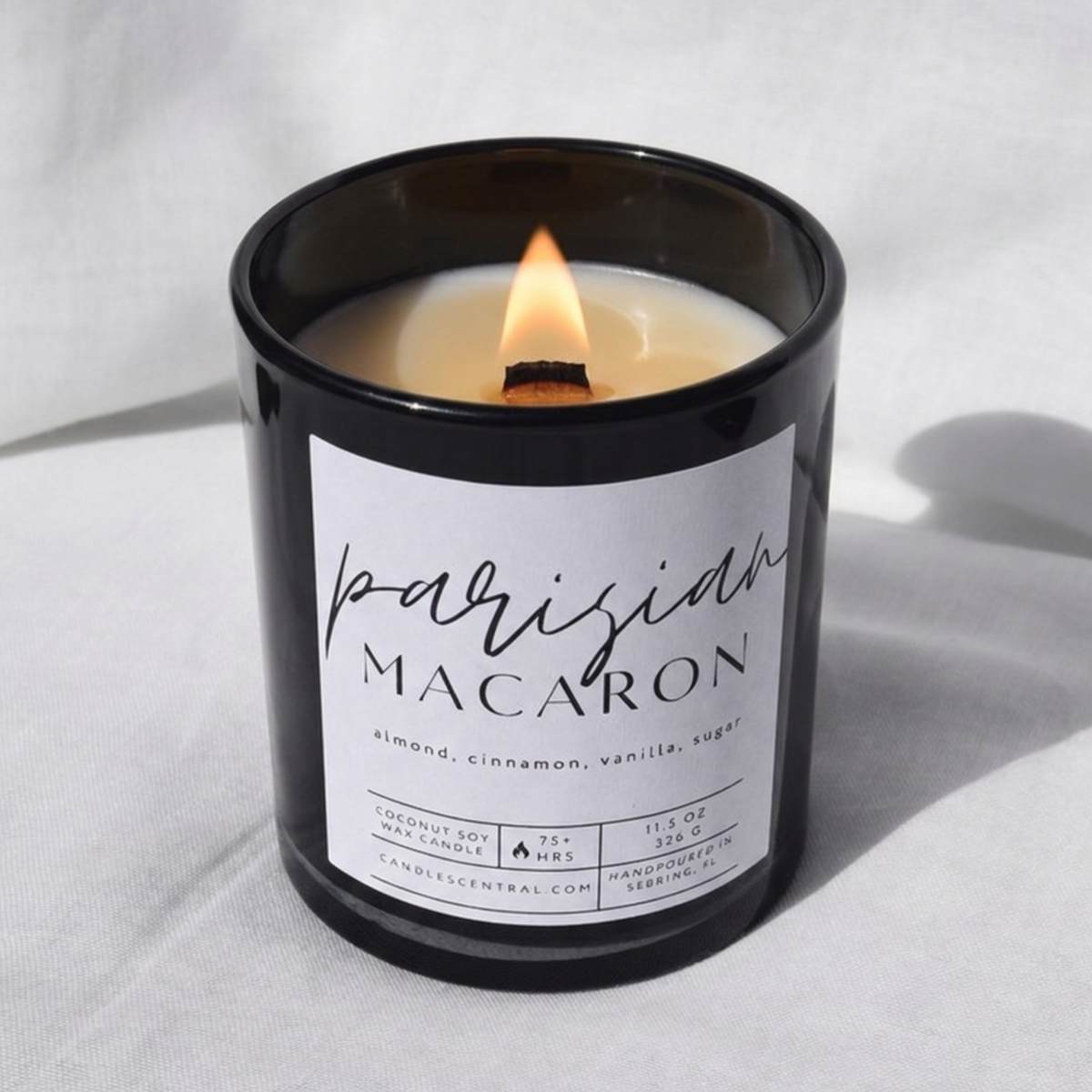 Picture of a candle burning with a label that says "Parisian Macaron" along with the fragrance notes of almond, cinnamon, vanilla, and sugar