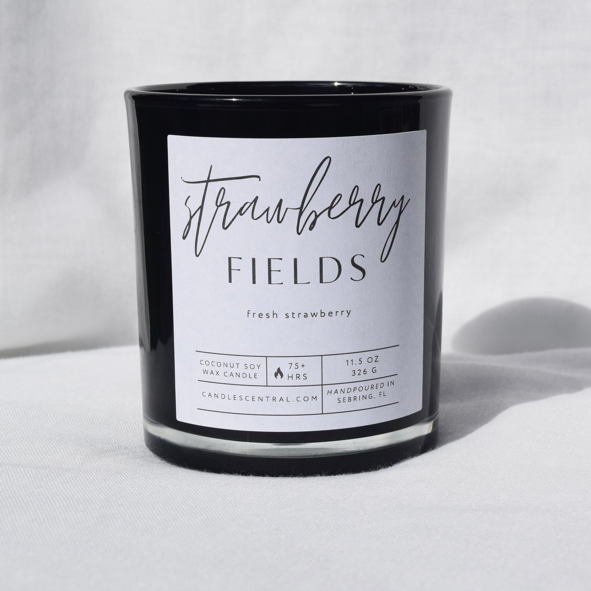 Picture of a candle with a label that says "Strawberry Fields" along with the fragrance note of fresh strawberry.