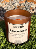 An amber glass candle with a label that says "Sunset on Marco" along with a short blurb reading "Bright bergamot, sea salt, and soft ocean air-- feels like Marco Island as the Sun sets and the tide drifts in."