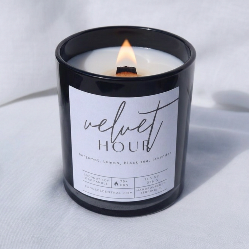 Picture of a candle burning with a label that says "Velvet Hour" along with the fragrance notes of bergamot, lemon, black tea, and lavender